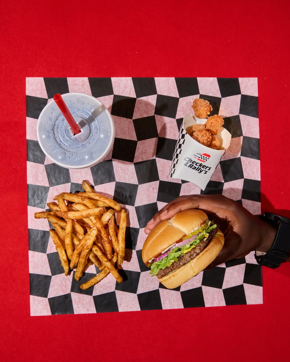 Checkers & Rally's burger, fries, chicken bites, and drink on branded checkered paper