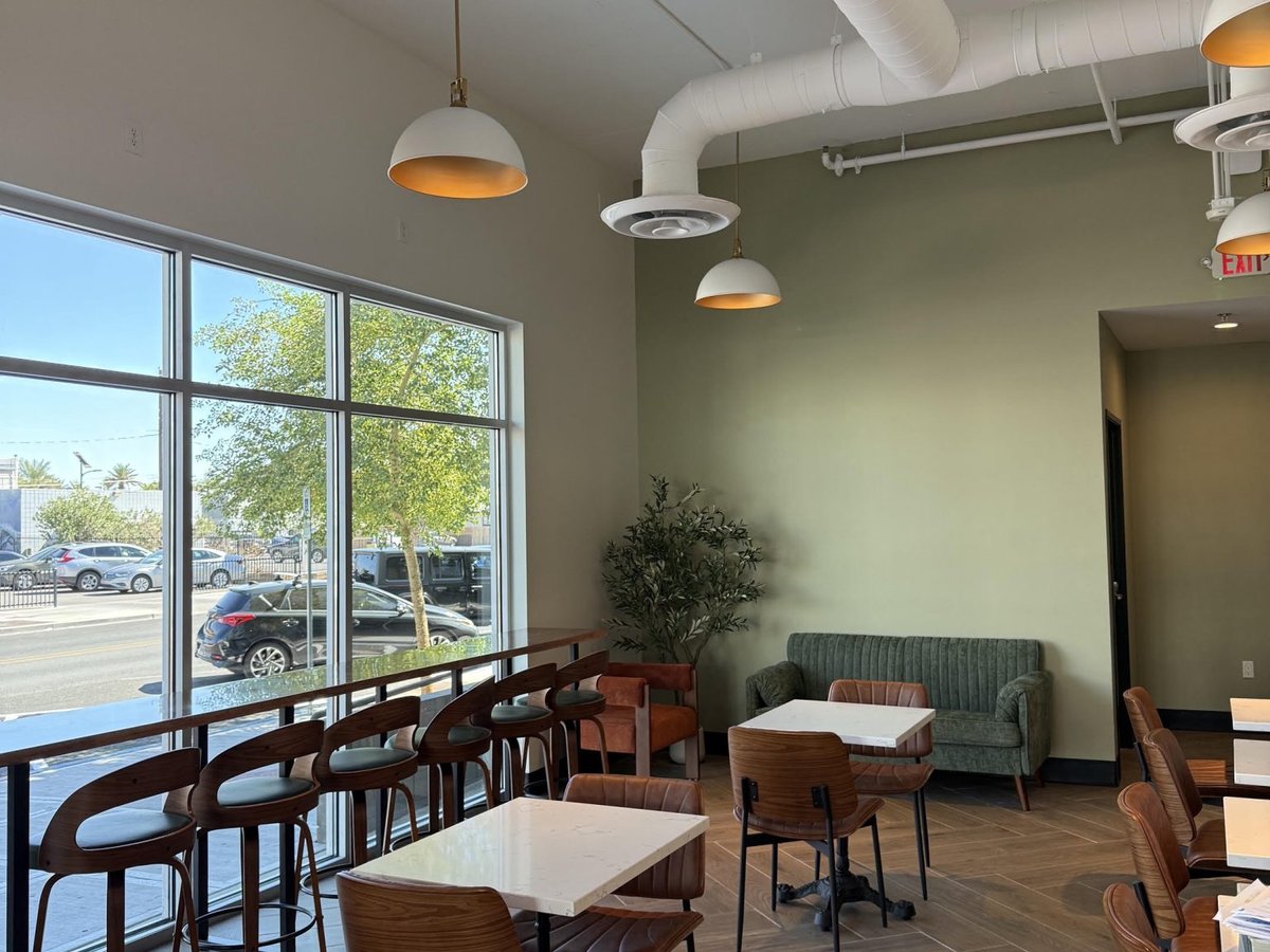 The new Almond & Oat cafe in the Arts District, with a window bar, a green banquette and small tables (official photo)