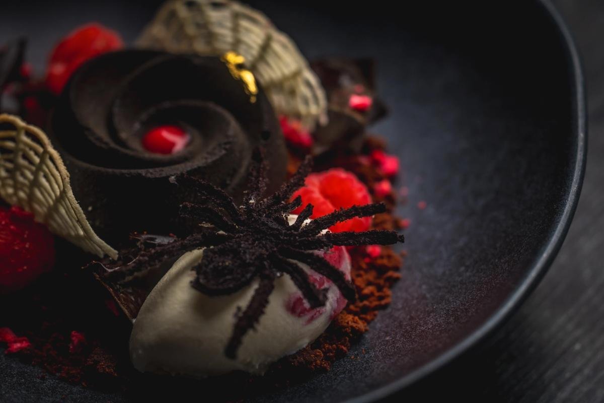 The Poisoned Rose, a dark raspberry dessert, on a black plate at Toca Madera (official photo)