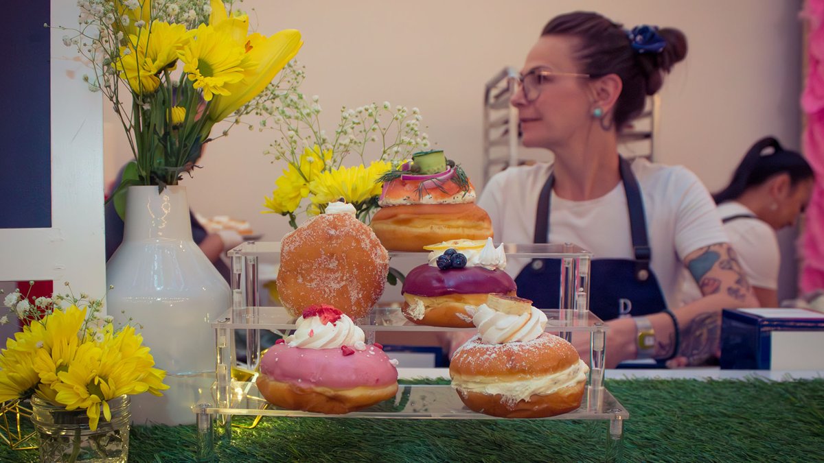 A chef stands behind a table of decorated pastries at a past Picnic in the Alley (official photo)