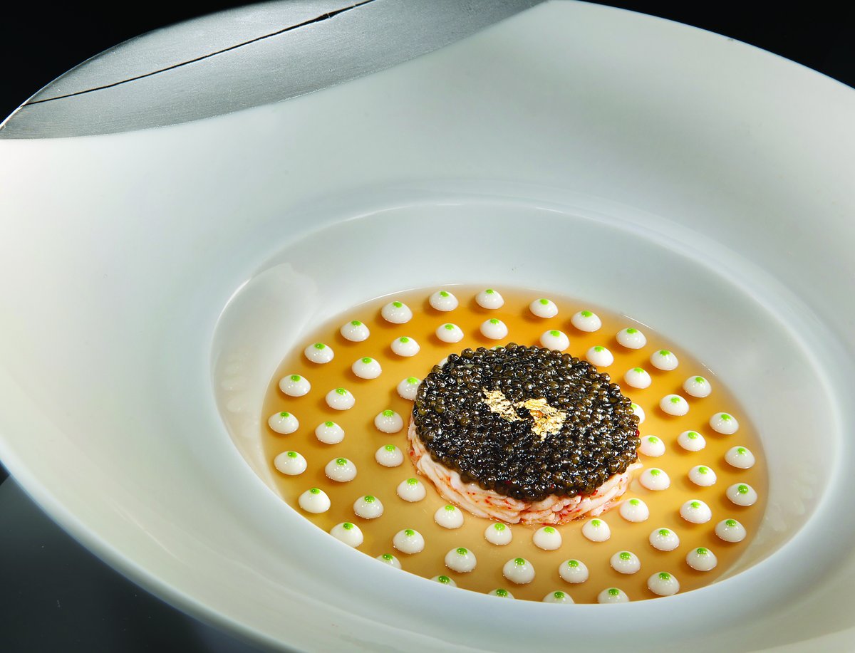 Caviar over crab in a golden gelée dotted with cauliflower purée in a wide white bowl at Joël Robuchon (MGM Resorts photo)