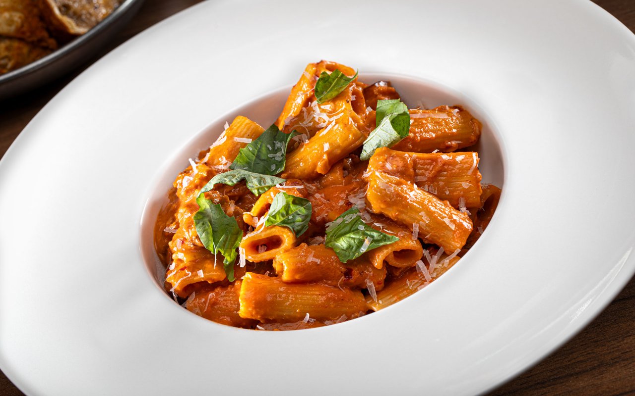 A white bowl of sausage rigatoni in a creamy tomato sauce with basil and Parmesan (Butcher & Thief photo)