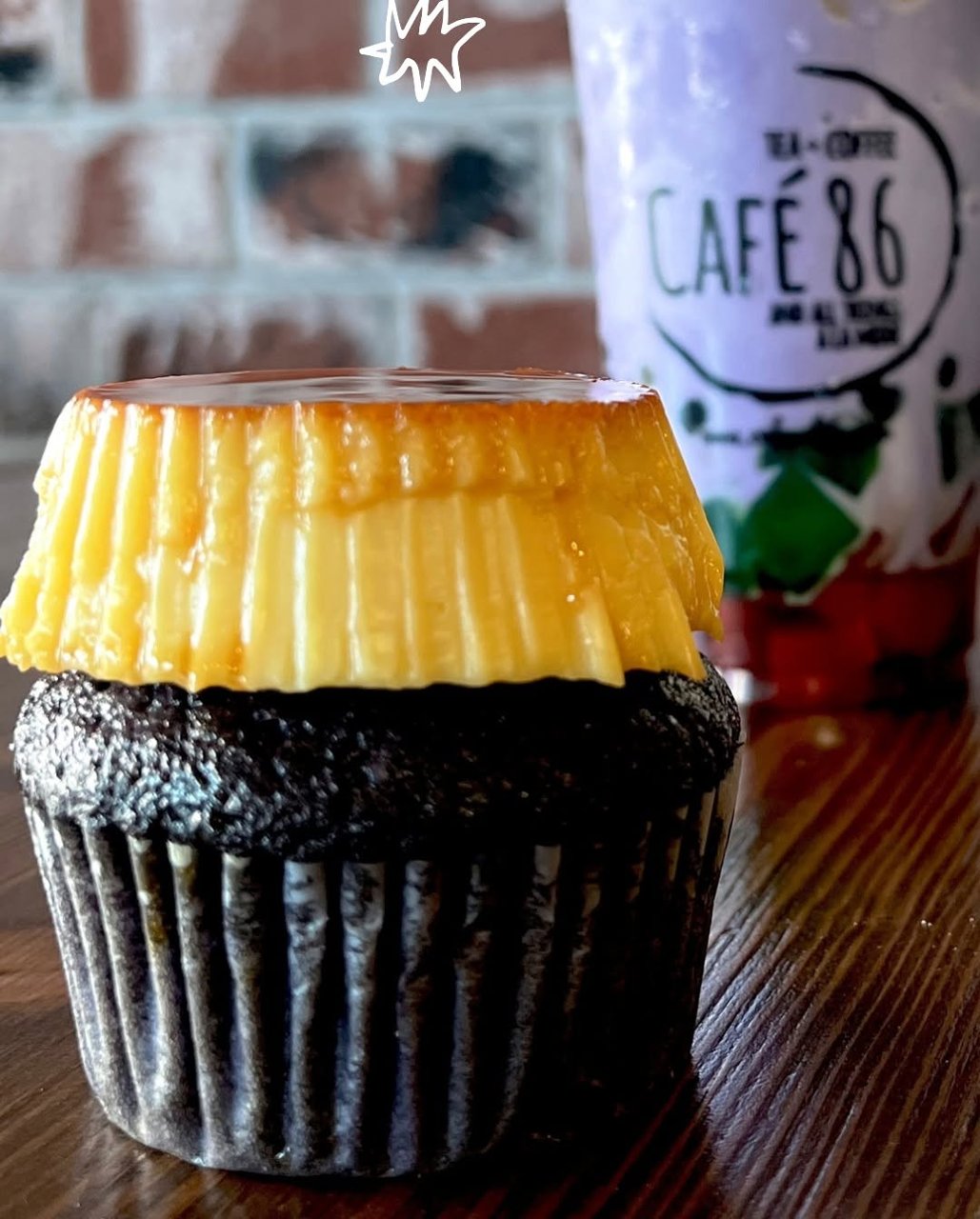 A chocolate ube cupcake topped with a whole leche flan, with a purple Cafe 86 drink behind it (Cafe 86 photo)