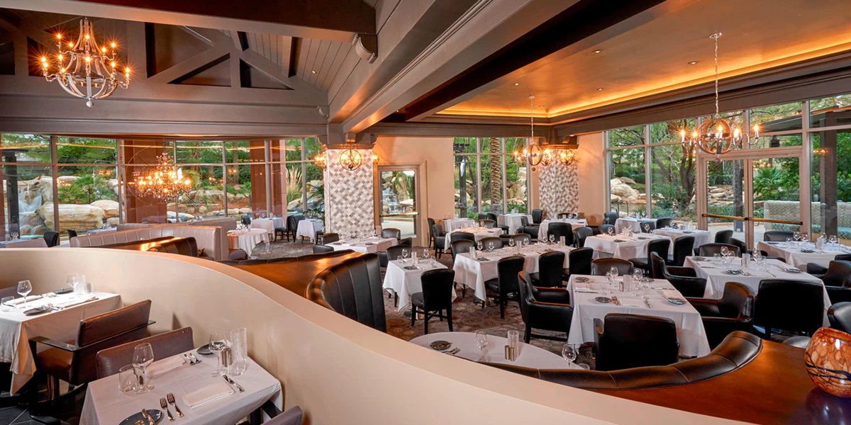 Hawthorn Grill's dining room with white tablecloths, chandeliers and tall windows onto a garden (Resort at Summerlin photo)