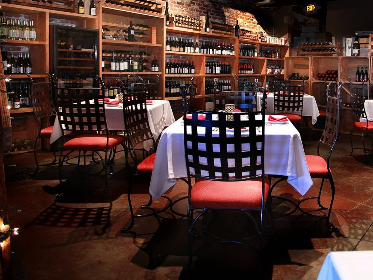 Grape Vine Café's wine cellar dining room, with a brick wall, wooden wine racks and tables set with red napkins (Grape Vine Café photo)