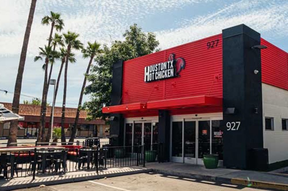 A red Houston TX Hot Chicken storefront with a patio and palm trees at another location (Houston TX Hot Chicken photo)